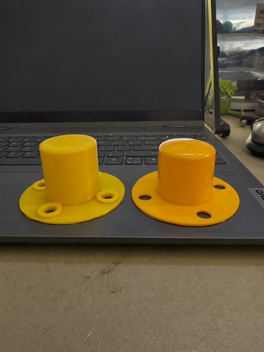 Two yellow delineator caps viewed at an angle: our 3D-printed replica on the left and the original reference cap on the right.