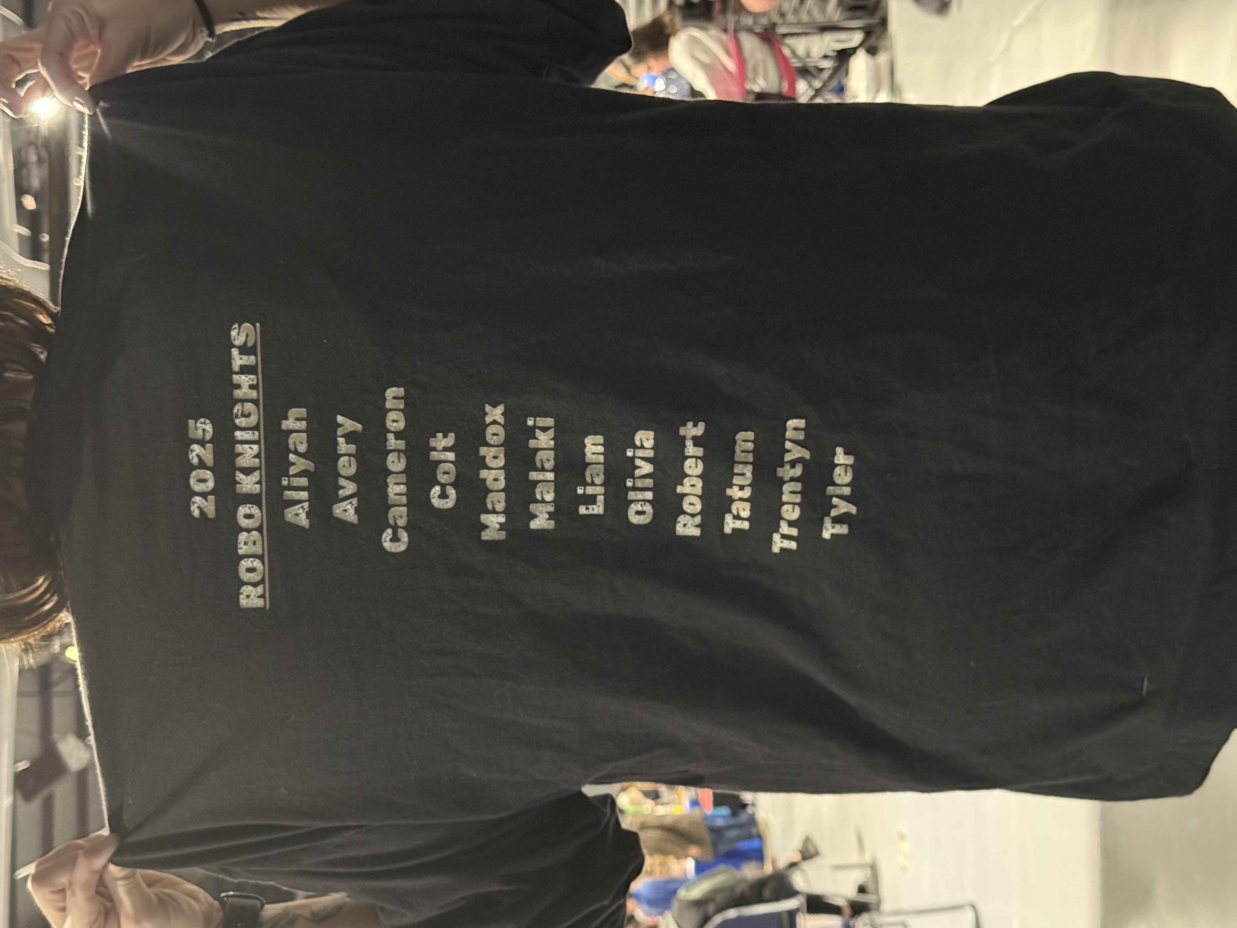 Back of a dark shirt with 2025 Robo Knights lettering and a vertical team roster.